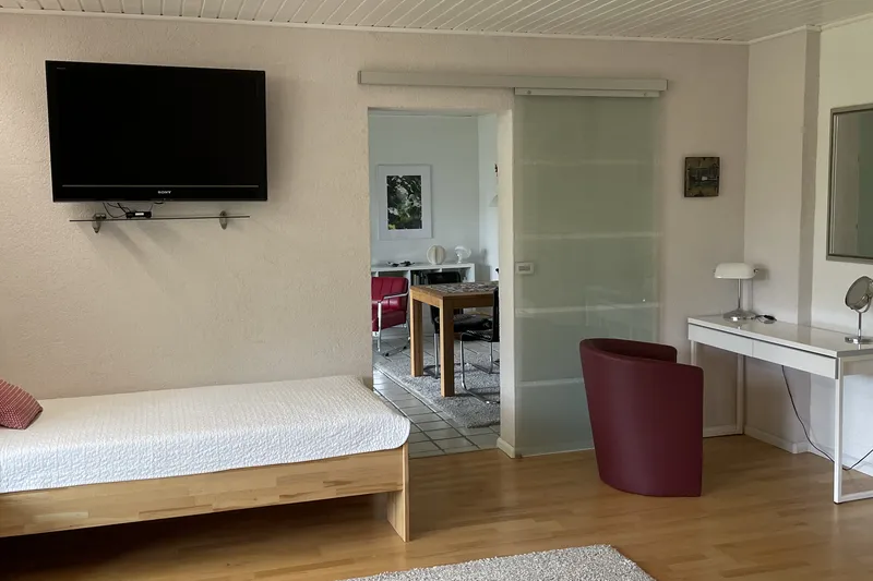 Single bed with TV and view of the dining area